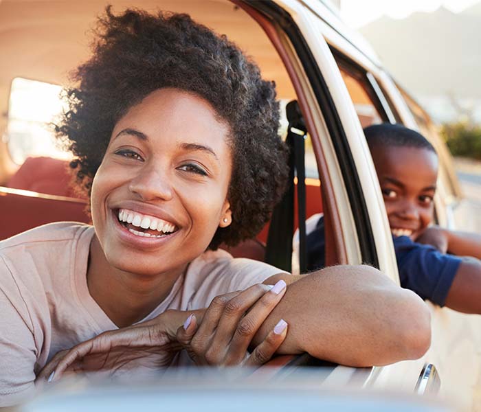 woman and son leaning out of window of car smiling
